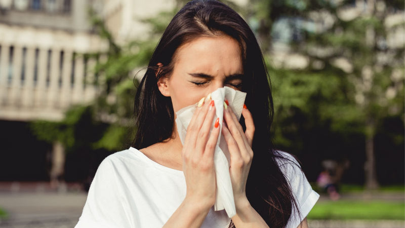 woman sneezing into tissue 