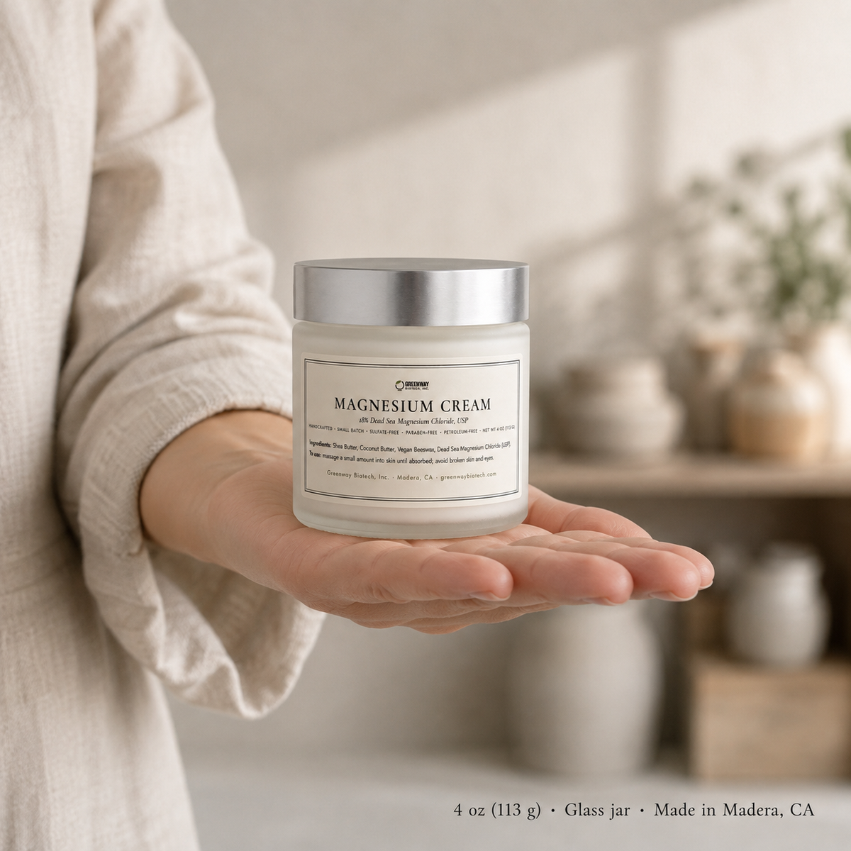 Magnesium Cream 4 oz glass jar held in an open palm to show its size