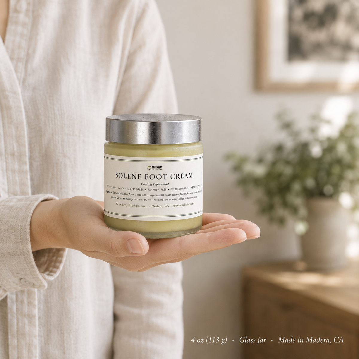 Solene Foot Cream 4 oz glass jar held in an open palm to show its size
